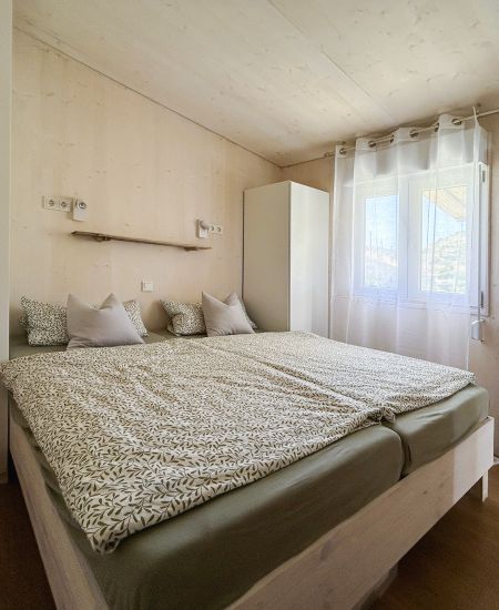 Tinyhouse sleepingroom with double bed and 2 big armchairs